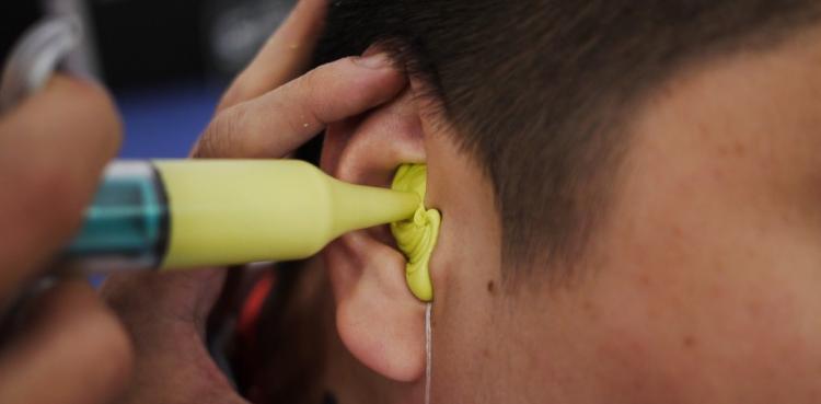 medical-professional-using-custom-earmold-impression-syringe-for-hearing-aid